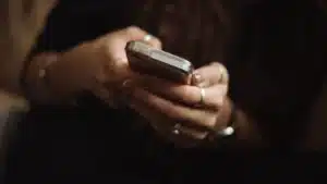 Silueta de una mujer junto a una ventana con el teléfono, antes de denunciar violencia de género en Alicante